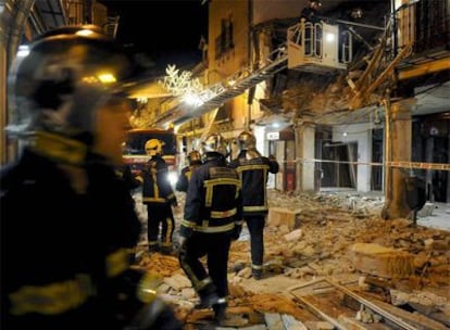 Bomberos en el lugar en el que se ha producido el derrumbe de parte de una fachada y de la cubierta de una casa de dos alturas en el número 85 de la calle Mayor de Alcalá de Henares.