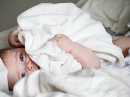 Un bebé tumbado en la cama. 