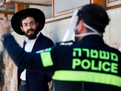 Un policía con mascarilla desaloja a un ultrarreligioso de un centro de estudios rabínico, el jueves en Bnei Brak, en la periferia sur de Tel Aviv (Israel).