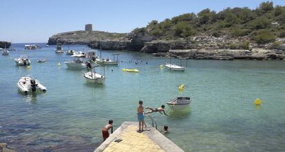 Varios ni&ntilde;os disfrutan de las altas temperaturas en la Cala de Alcafar en Menorca.