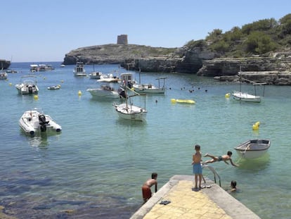 Varios ni&ntilde;os disfrutan de las altas temperaturas en la Cala de Alcafar en Menorca.