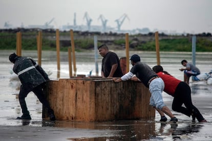 Tabajadores retiran sus pertenencias de la playa ante el fuerte oleaje de la costa.