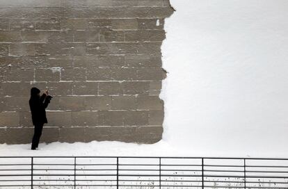 Una persona toma imágenes de un muro cubierto de nieve cerca del río Spree en Berlín (Alemania), el 6 de enero de 2016.