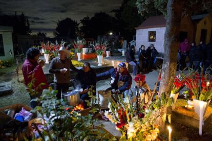 Cementerio de San Gregorio en la ciudad de México, en las primeras horas de la mañana del domingo. Las familias decoran las tumbas de parientes fallecidos con caléndulas y velas,