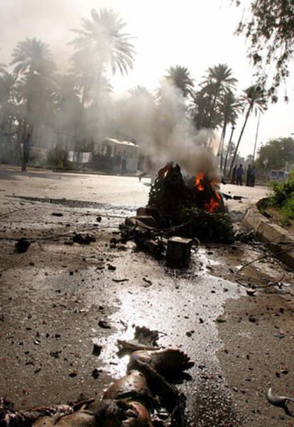 Un cadáver yace junto al coche que hizo estallar un terrorista suicida ayer en Bagdad.