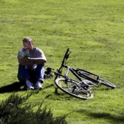 Un hombre disfruta del buen tiempo en una pradera del madrileño Paseo del Prado, durante el último día de invierno