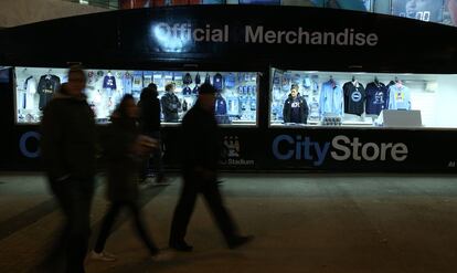 Aficionados caminan por las calles aledañas al estadio Etihad del Manchester City. A su lado, la tienda oficial del club británico.