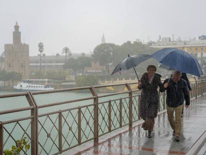 Peatones cruzan bajo la lluvia el puente de los Remedios en Sevilla, el pasado día 22.