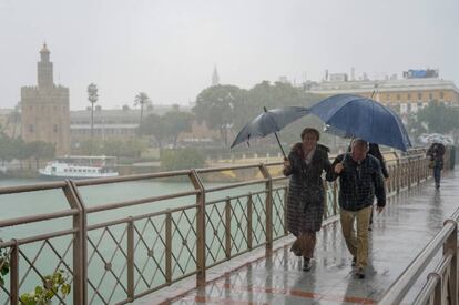 Peatones cruzan bajo la lluvia el puente de los Remedios en Sevilla, el pasado día 22.