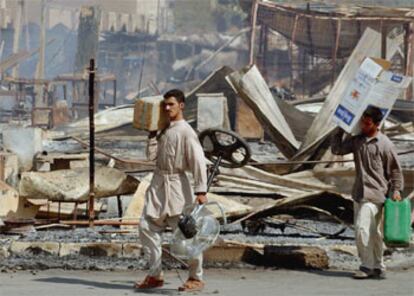 Habitantes de Nayaf cargan enseres junto a los escombros a que han quedado reducidos muchos edificios como consecuencia de los combates.