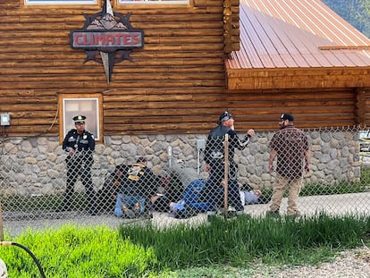 A police officer stands guard as a man with a Bandidos MC patch assists a shot biker in Red River, New Mexico after a shootout between members of two motorcycle gangs, on May 27, 2023.