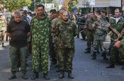 Combatientes prorrusos (derecha) vigilan a una columna de prisioneros ucranios en Donetsk, en agosto