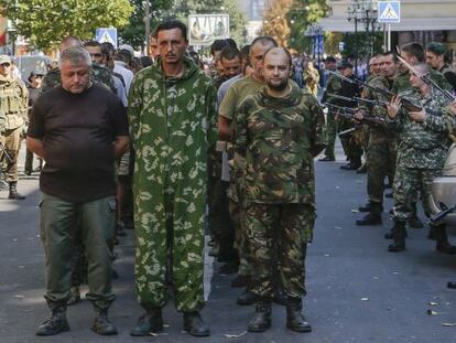 Combatientes prorrusos (derecha) vigilan a una columna de prisioneros ucranios en Donetsk, en agosto