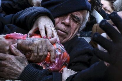 Un hombre agarra una bolsa de mandarinas que le entregan unos agricultores griegos durante una protesta contra la propuesta del gobierno para reformar el sistema de pensiones, en Atenas.