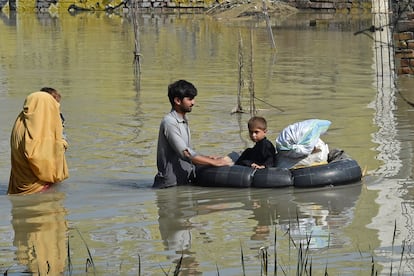 Una familia vadea a través de una zona afectada por las inundaciones, en el distrito de Charsadda de Khyber Pakhtunkhwa, el 29 de agosto de 2022. 