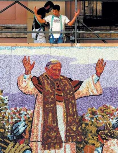 Dos trabajadores dan los últimos toques a un mosaico del Papa junto a la basílica de los Desamparados.