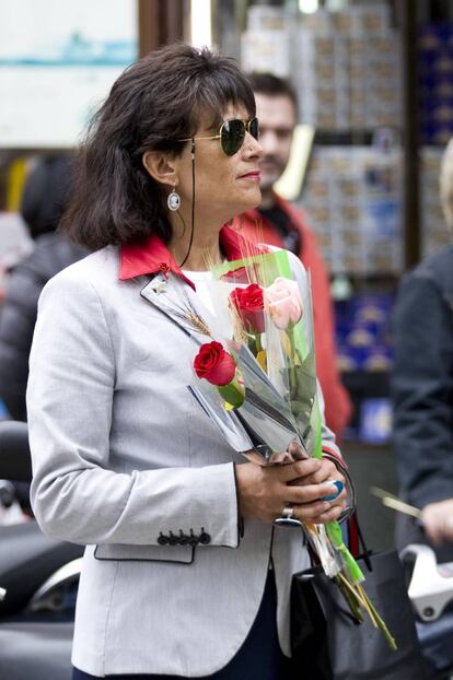 Una mujer pasea con un puñado de rosa por la rambla de Catalunya durante la tarde del Sant Jordi.