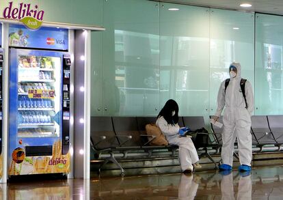 Dos pasajeros equipados con un EPI esperan su vuelo en el aeropuerto de Barcelona, el viernes.