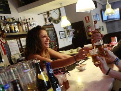 Una camarera y varios clientes de un bar de Madrid.