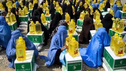 Mujeres afganas, vestidas con burka, esperan sentadas la ayuda de una organización benéfica durante el mes sagrado de Ramadán en la provincia de Herat.