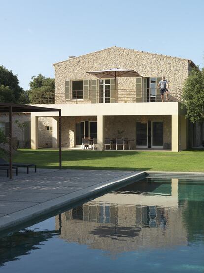 La terraza del dormitorio principal y el salón de la casa tienen vistas a la piscina y al comedor bajo la pérgola del jardín trasero.