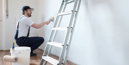 Imagen de un pintor repasando la pared de una casa. 