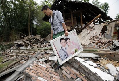 Lushan, China, 21 de abril de 2013. Un hombre recupera su foto de boda de las ruinas de su casa tras el terremoto en el municipio de Longmen, en la provincia china de Sichuan. Cinco años después del terremoto que sacudió el suroeste de China con un balance de 87.000 muertos y desaparecidos, la tierra volvió a temblar con fuerza en la misma zona. Al menos 102 personas fallecieron y 3.000 resultaron heridas.