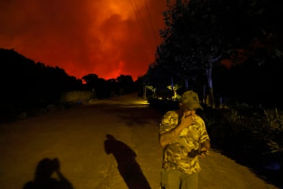 Un hombre sigue por el movil los avances del incendio.