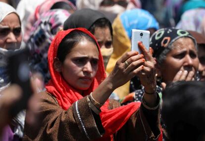 Una mujer musulmana de Cachemira utiliza su tel&eacute;fono mientras asiste a la procesi&oacute;n f&uacute;nebre de un militante local asesinado en la zona de Panjran Lassipora, en la India.