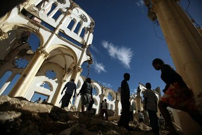 Haitianos caminan entre los escombros de la catedral de Puerto Príncipe durante la misa oficiada en hoy, justo un año después del terremoto en el que murieron más de 200.000 personas.