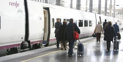 Viajeros junto a un tren AVE de Renfe.