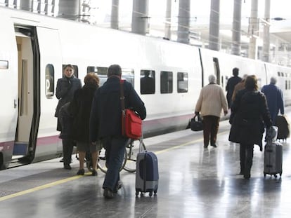 Viajeros junto a un tren AVE de Renfe.