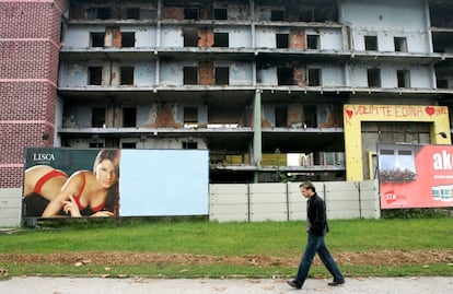 Un transeúnte de Sarajevo, camina por la antigua avenida de los francotiradores, junto a un cartel publicitario.