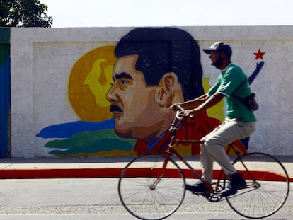 A man cycles past a mural of Venezuelan leader Nicolás Maduro.