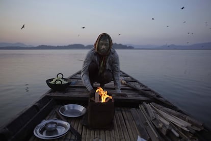 Un pescador prepara un fuego para cocinar antes de salir a pescar en el río Brahmaputra en Gauhati (India).