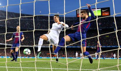 Cristiano marca ante Piqué e Iniesta en el Barcelona-Real Madrid (2-2), en partido de Liga, en el Camp Nou, en 2018.