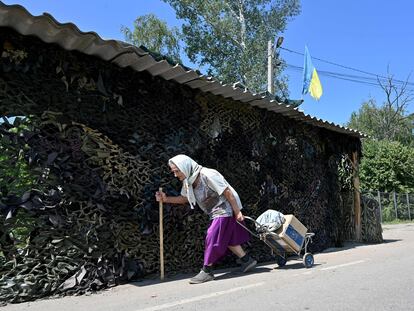 Una mujer lleva una caja de comida del Programa Mundial de Alimentos de la ONU, distribuidos por voluntarios, como ayuda humanitaria a los residentes locales de la aldea de Liptsy, región de Kharkiv, a unos 10 km de la frontera con Rusia, el 22 de junio de 2023,