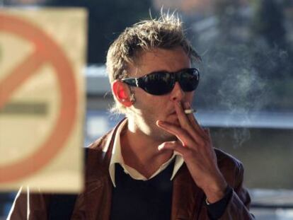 Un hombre fuma en la puerta de un bar de Madrid ante un cartel de prohibición