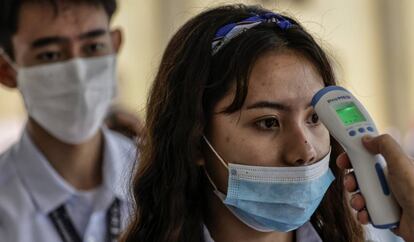 Personal de seguridad toma la temperatura a los estudiantes que entran a una universidad de Manila (Filipinas).