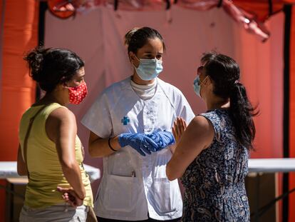 Una sanitaria conversa con dos mujeres en Ripollet el 8 de agosto (Barcelona).