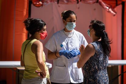 Una sanitaria conversa con dos mujeres en Ripollet el 8 de agosto (Barcelona).