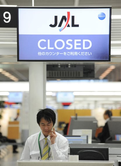 Un trabajador de Japan Airlines ante un mostrado de facturación cerrado en el aeropuerto internacional de la capital japonesa.