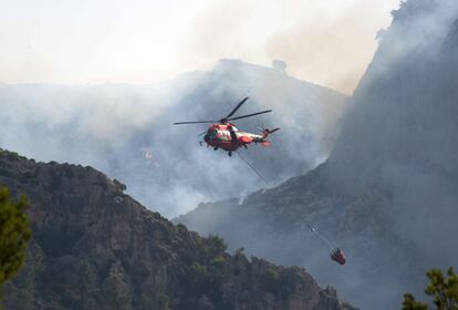 Un helicóptero trabaja en las labores de extinción del incendio que desde está calcinando cientos de hectáreas de los montes adyacentes a los municipios de Andratx y Estellens.