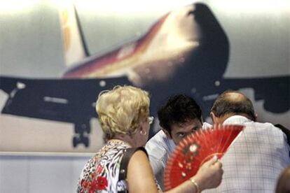 Dos viajeros hacen una consulta a un trabajador del aeropuerto de El Prat.