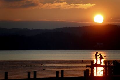 Una pareja se prepara para nadar en el lago Starnberger de Percha (Alemania) durante el atardecer.