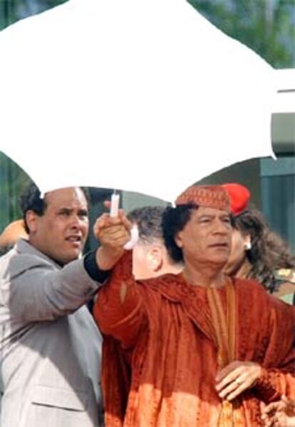 El líder libio Gadhafi se proteje del sol a su llegada a la cumbre árabe.