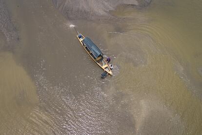 Tres hombres empujan una embarcación atascada en el lago El Correo, en Puerto Nariño.