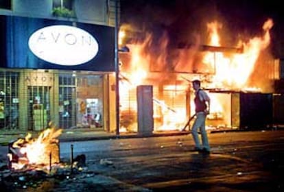 Un policía de paisano pasa delante de unas tiendas quemadas en el centro de Buenos Aires durante la noche del jueves.