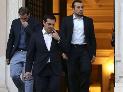 El primer ministro griego, Alexis Tsipras, flanqueado por el ministro de  Presidencia Nikos Pappas (derecha) y el portavoz Gabriel Sakelaridis, abandona sus oficinas para visitar al presidente Prokopis Pavlopoulos, ayer en Atenas.