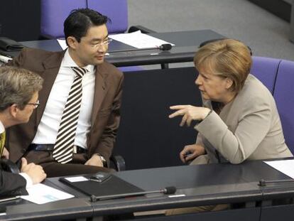 La canciller alemana, Angela Merkel, conversa con el ministro alemán de Exteriores, Guido Westerwelle (izda), y el ministro alemán de Economía, Phillip Rösler (centro), durante una sesión parlamentaria en Berlín.